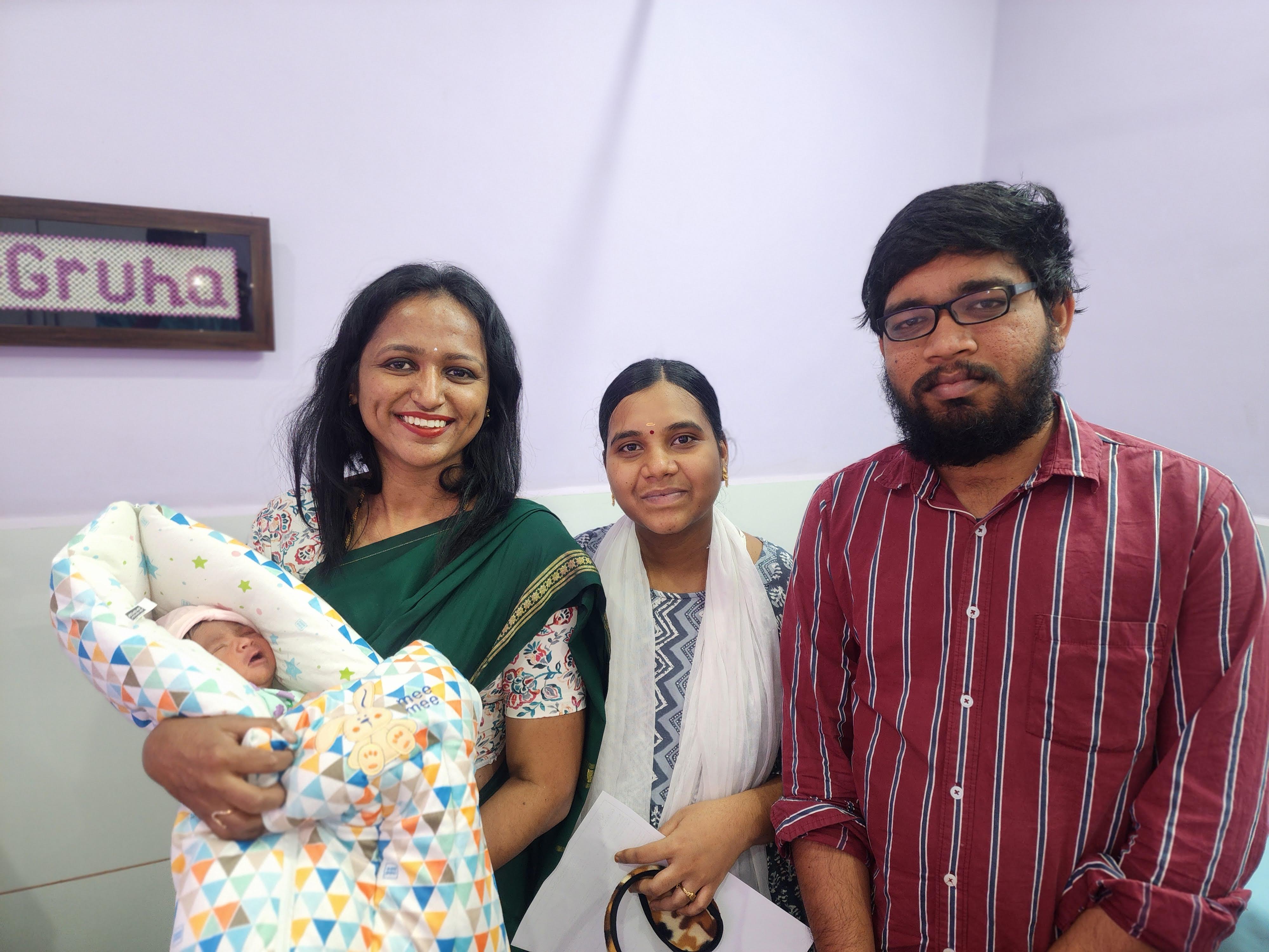 Dr. Rashmi T N with new parents and their newborn at GarbhaGruha Health Center