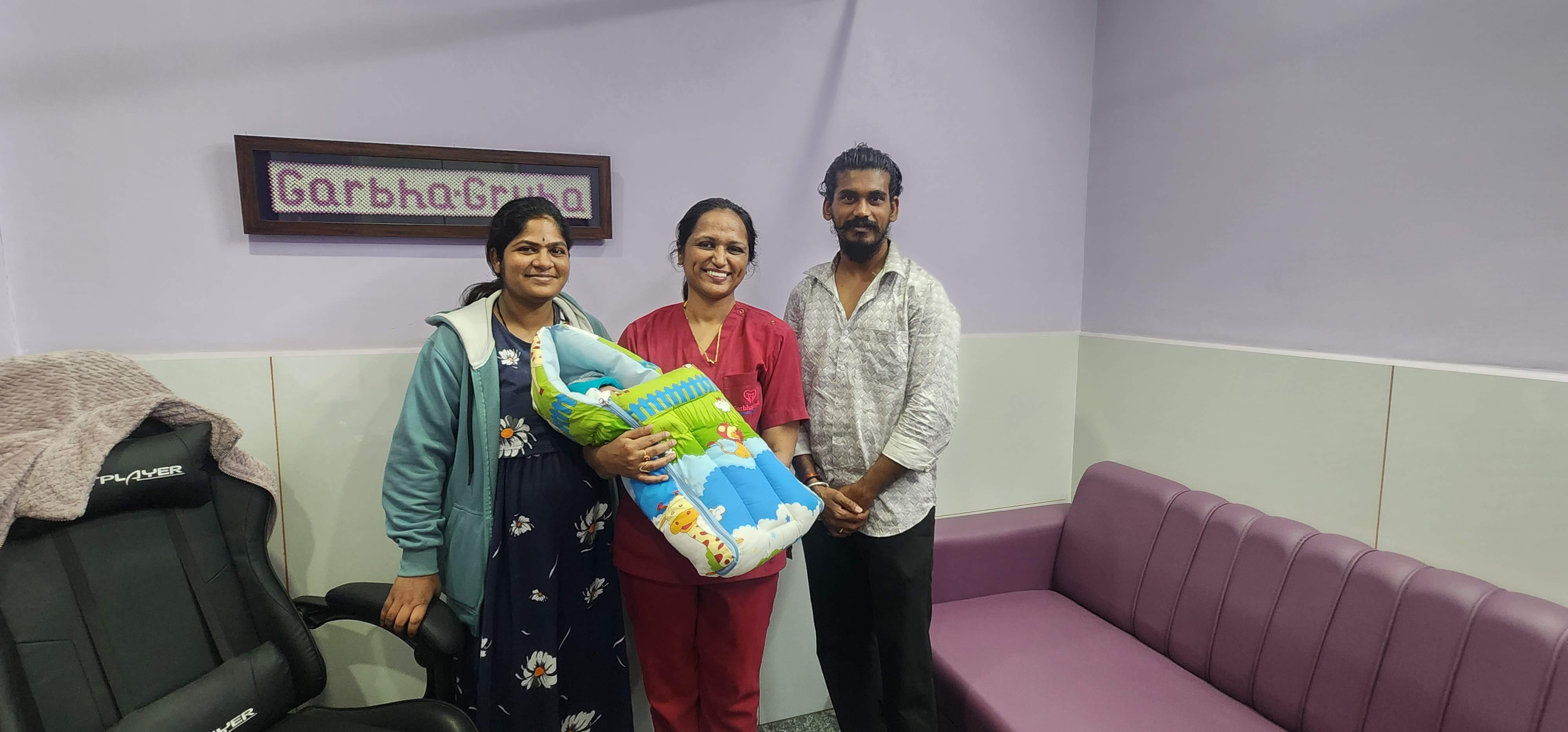 GarbhaGruha staff holding a newborn with happy parents at discharge